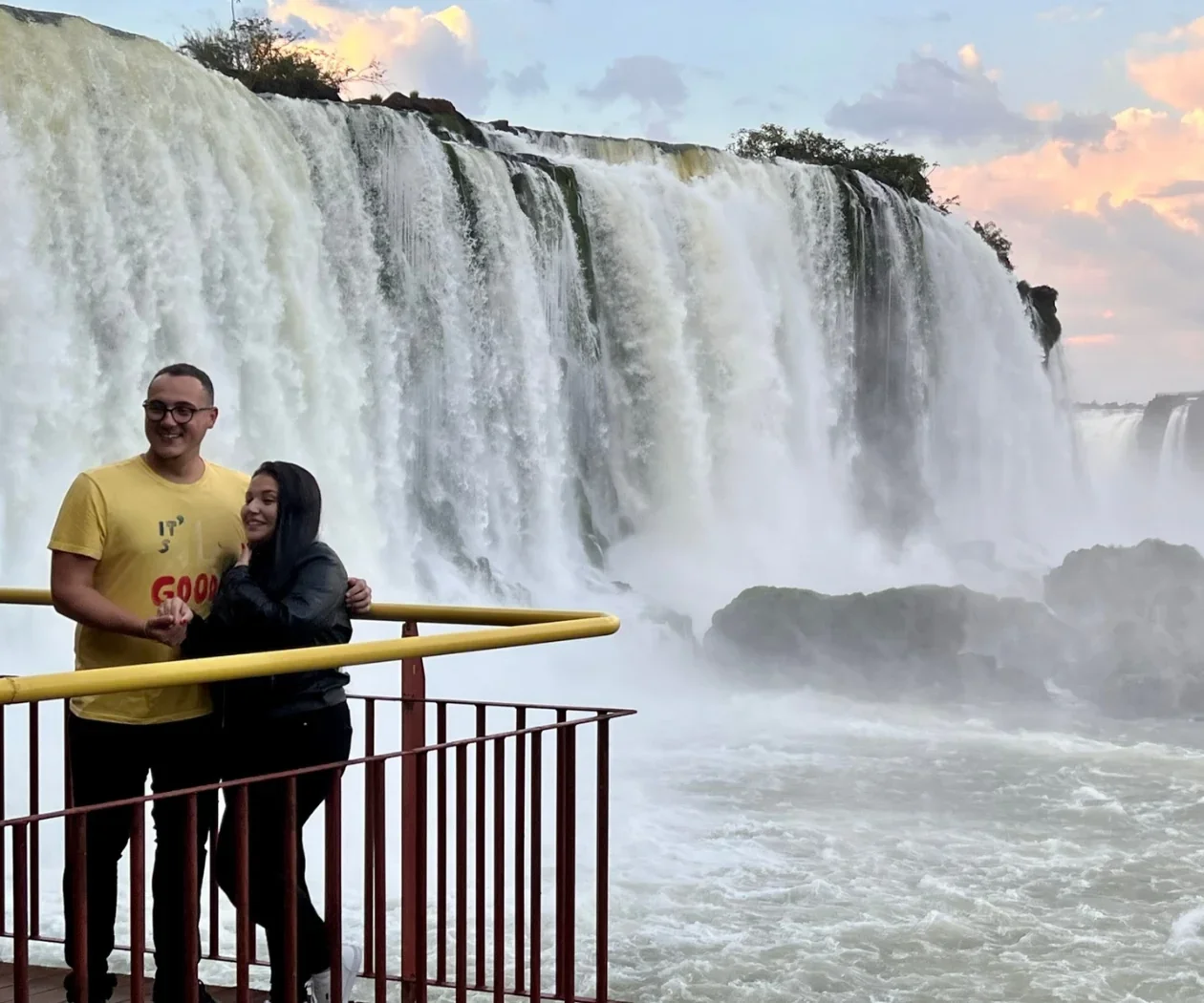 Casal no Amanhecer das Cataratas com placa icônica do Parque Nacional