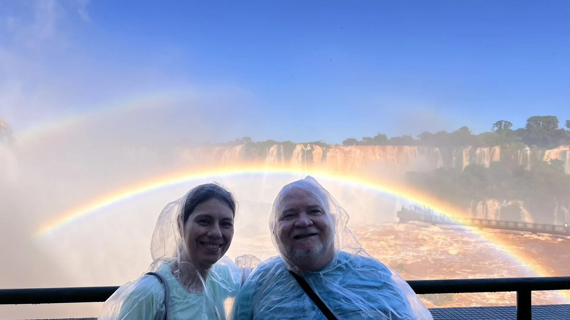 Casal em ponchos nas Cataratas do Iguaçu brasileiras com arco-íris duplo