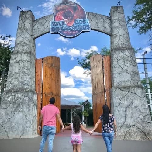 Família de mãos dadas no portão de entrada do Vale dos Dinossauros
